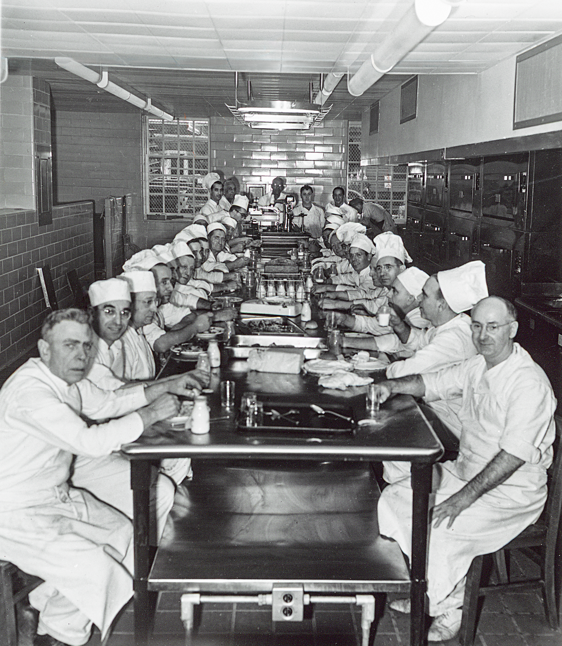 Ratty workers sit for dinner before service in the kitchen, 1050s